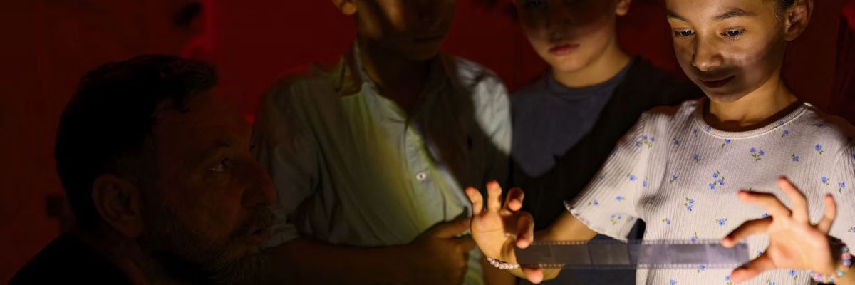Children look at developed film in a darkroom during an analog photography workshop held in southeastern Turkey on June 14, 2026.