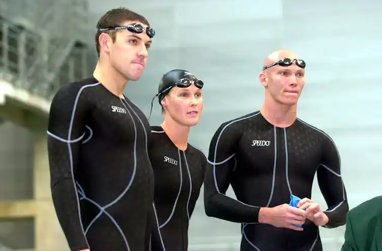 Three swimmers in black bathers.
