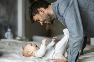 A father smiling down at his infant as the infant smiles back